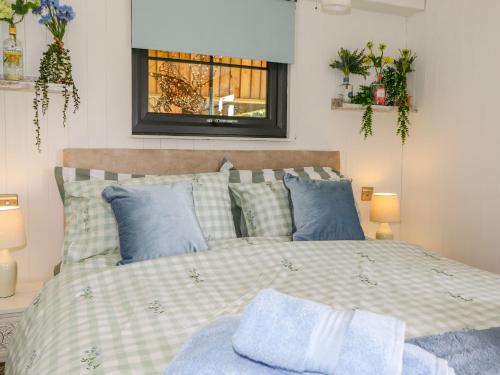 a bedroom with a bed with blue pillows and a window at High Rigg Shepherd's Sunrise in Brampton
