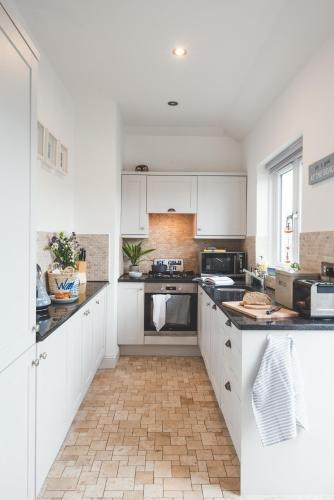 a kitchen with white cabinets and black counter tops at Waves - Sea View Duplex Apartment, Stoke Fleming in Stoke Fleming