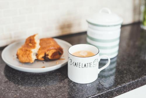 a plate of food and a cup of coffee on a counter at Waves - Sea View Duplex Apartment, Stoke Fleming in Stoke Fleming