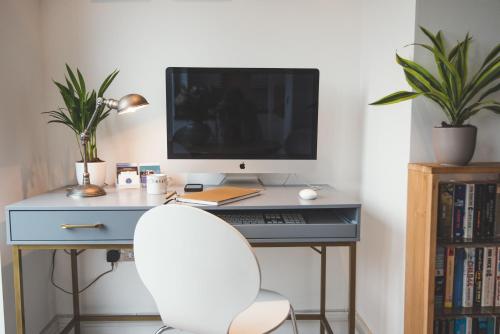 a desk with a computer monitor and a white chair at Waves - Sea View Duplex Apartment, Stoke Fleming in Stoke Fleming
