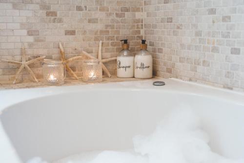 a bath tub with two bottles and candles on it at Waves - Duplex Apartment Stoke Fleming in Stoke Fleming
