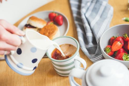 a table with a plate of strawberries and a cup of coffee at Waves - Sea View Duplex Apartment, Stoke Fleming in Stoke Fleming