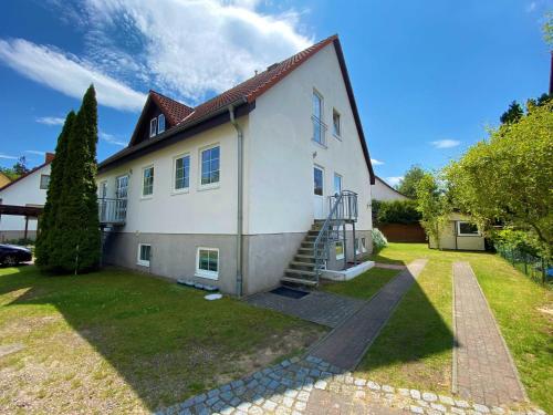 a large white house with a staircase in the yard at Ferienhaus Ruegenliebe 01 in Binz