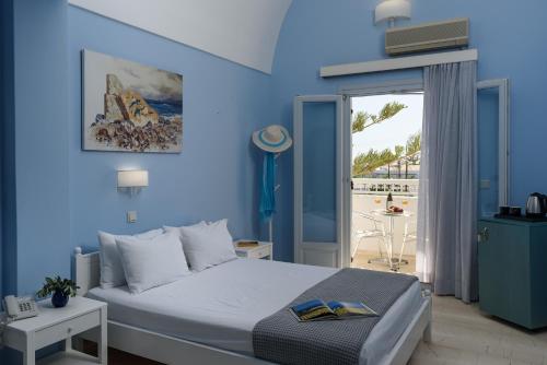 a blue bedroom with a bed and a balcony at Glaros Hotel in Kamari
