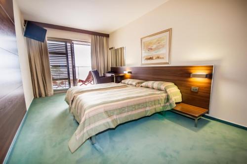 Pokój hotelowy z łóżkiem i krzesłem w obiekcie Hotel Maxim w mieście Božava
