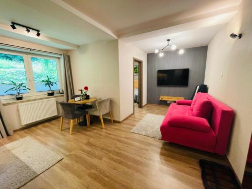 a living room with a red couch and a table at Apartament Góry i Potok in Porąbka