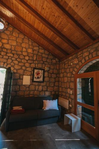 a living room with a couch in a stone wall at River huts Zrmanja in Obrovac