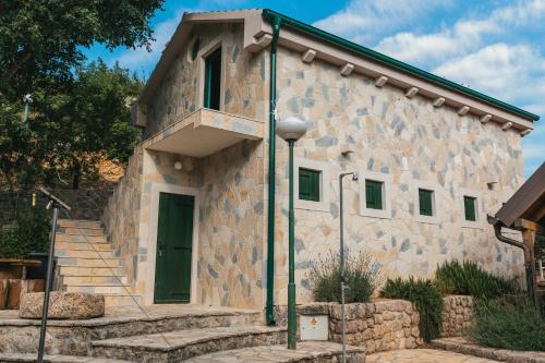 a stone building with a green door and stairs at River huts Zrmanja in Obrovac