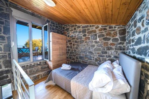a bedroom with a bed and a stone wall at TerraZeus - Stone House Beachfront 1 in Milatos