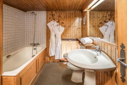 La salle de bains est pourvue d'un lavabo, d'une baignoire et de toilettes. dans l'établissement Madame Vacances Chalet Val Rogoney, à Val dʼIsère