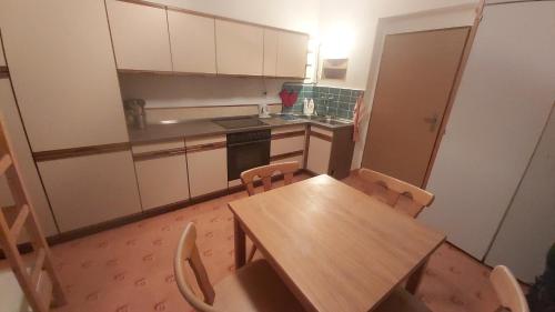 a small kitchen with a wooden table and chairs at Penzion Diana in Železná Ruda