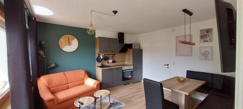 a living room with an orange chair and a table at Gailtaler Apartments Alinkhof in Bach