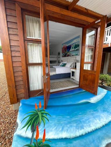 a room with a bed and an open door to the ocean at Happy Waves Holiday Home in Jeffreys Bay