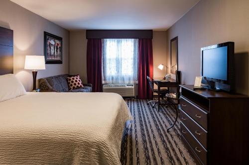um quarto de hotel com uma cama e uma televisão de ecrã plano em Colonial Hotel em Gardner