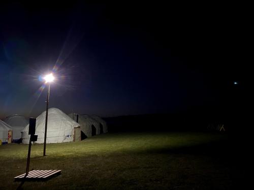 a light pole with tents in a field at night at Yurt Camp Ali-Nur, Lake Song-Kul , Kyrgyzstan, Юрточный лагерь Али Нур, на берегу озера Сон Кол in Naryn