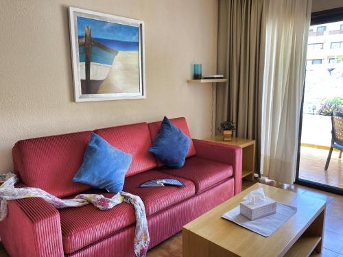 salon z czerwoną kanapą i niebieskimi poduszkami w obiekcie Walk to Golf heated pool Apartment w San Miguel de Abona