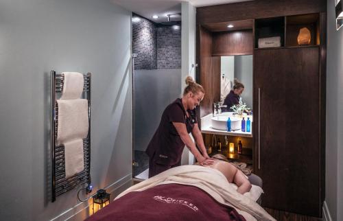 a woman in a bathroom with a man laying on a bed at Norton House Hotel & Spa, Edinburgh in Ingliston