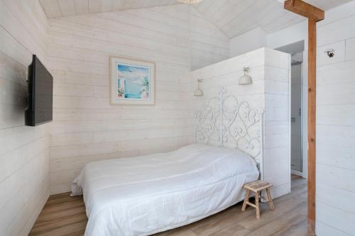 a white bedroom with a bed and a tv at Ty Maria Havre de douceur et de calme au coeur de la ville haute de Pornic in Pornic