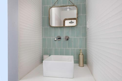 La salle de bains est pourvue d'un lavabo blanc et d'un miroir. dans l'établissement Ty Maria Havre de douceur et de calme au coeur de la ville haute de Pornic, à Pornic