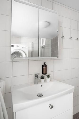 a white bathroom with a sink and a mirror at Forenom Hotels & Apartments Flemingsberg - 10min from Älvsjö in Huddinge