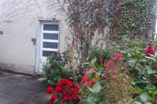 - un jardin avec des fleurs rouges devant une porte dans l'établissement LE CAMELIA, à Éguzon-Chantôme