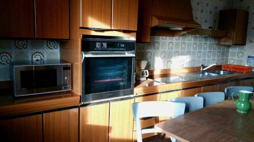 a kitchen with a microwave and a table with chairs at Gîte la fourmilière in Morbier