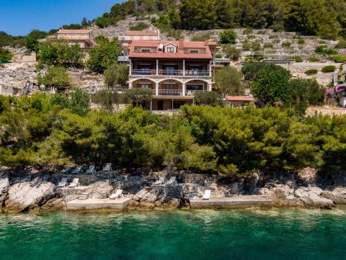 a house on a hill next to a body of water at Villa Amfora in Prizba