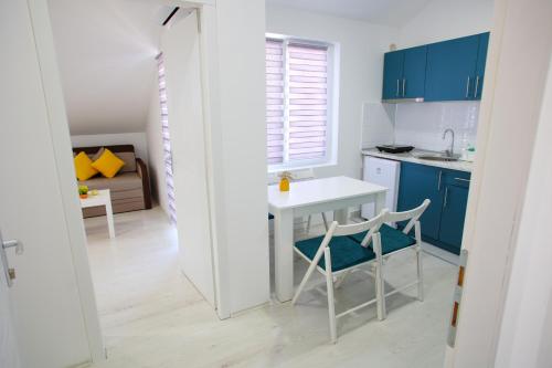 a kitchen with blue cabinets and a white table and chairs at Apartmani Hedonist in Soko Banja