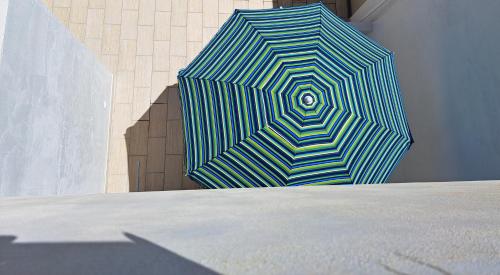 un ombrello blu e bianco seduto accanto a un muro di Casa vacanze Anticaglie a Punta Secca