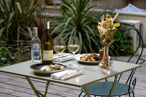 a table with two plates of food and wine glasses at Hôtel Maison Montgrand - Vieux Port in Marseille