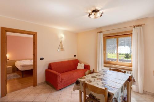 salon z czerwonym krzesłem i stołem w obiekcie Appartamento Valleverde w Livigno