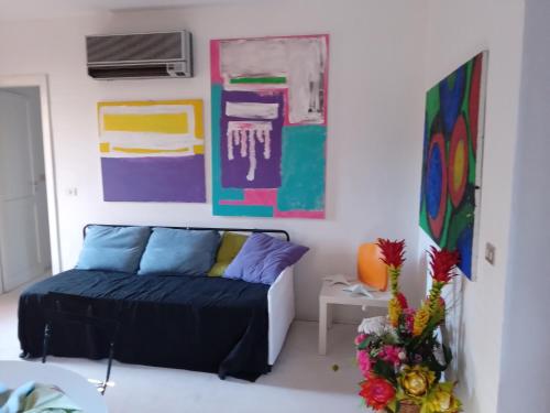 a living room with a couch and paintings on the wall at Casa Vacanze La Tonnara in San Giorgio