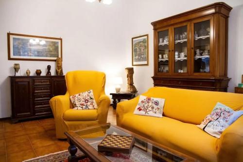 a living room with a yellow couch and two chairs at Amazing Tuscany Window in Montemassi