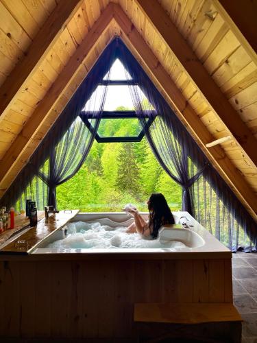 a woman is sitting in a bath tub at Riona dağ evleri in Çamlıhemşin