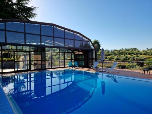 - une piscine avec 2 chaises en face d'un bâtiment dans l'établissement B&B Podere Montese, à Villafranca in Lunigiana