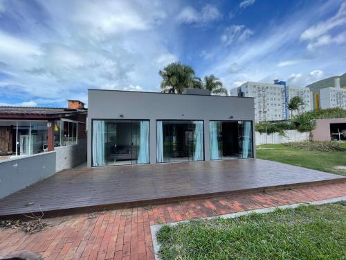 ein weißes Haus mit einer Holzterrasse in der Unterkunft Palhoça Casa na Praia de fora Palhoça - 30m do mar in Palhoça