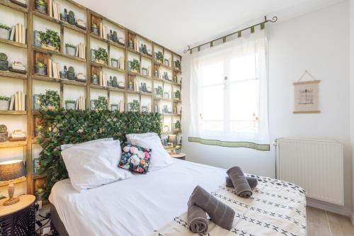 1 dormitorio con cama blanca y pared de libros en Family Travel Paris, en Bussy-Saint-Georges