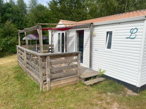 a white house with a wooden porch and a fence at domaine des planesses in Ferdrupt