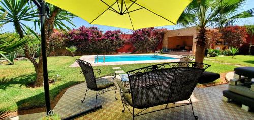 una sombrilla amarilla y sillas junto a una piscina en Belle maison de campagne en Kenitra