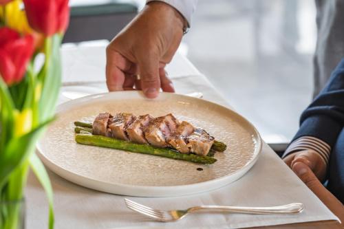 a person holding a plate with a piece of meat and asparagus at Conca Bella Boutique Hotel & Wine Experience in Vacallo