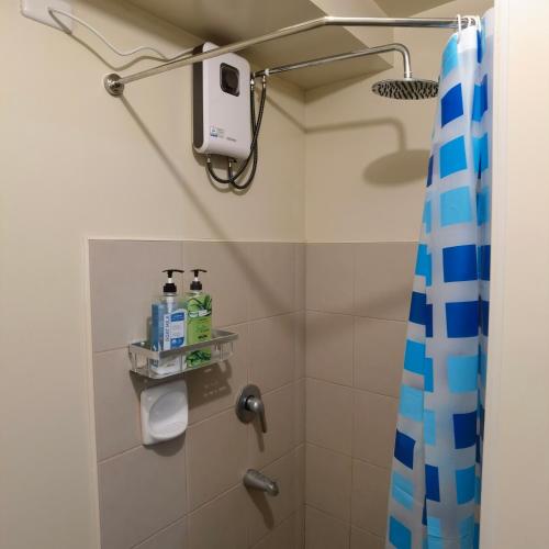 a shower in a bathroom with a blue shower curtain at Avida Davao Condos, downtown CM Recto Avenue, Davao City in Davao City