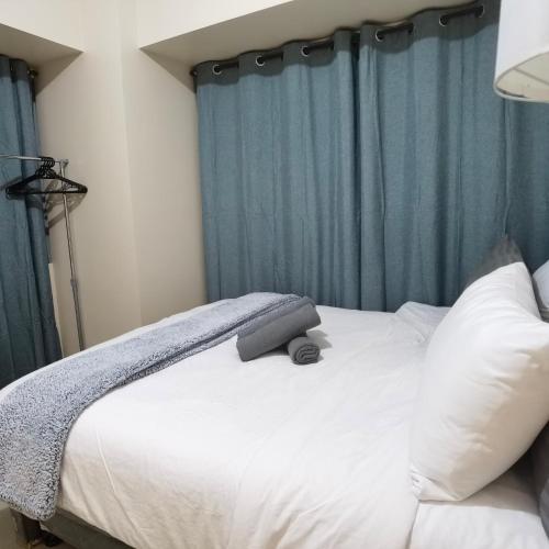 a bedroom with a white bed with blue curtains at Avida Davao Condos, downtown CM Recto Avenue, Davao City in Davao City