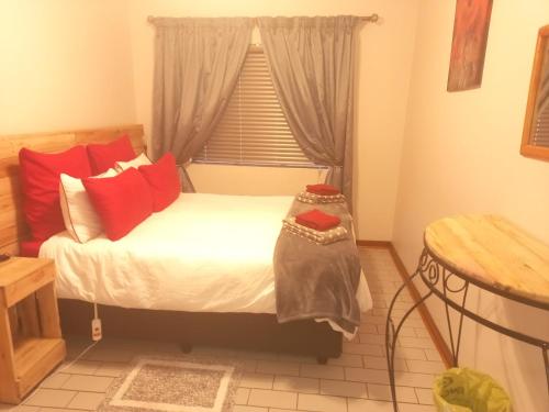 Un dormitorio con una cama con almohadas rojas y una ventana en ChriZelo Self Catering unit, en Upington