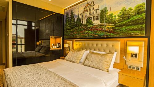 a bedroom with a bed with a large painting on the wall at Aselia Hotel Trabzon in Trabzon