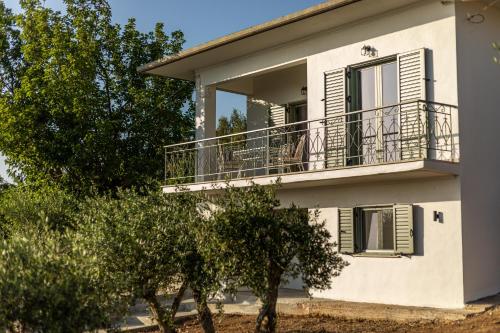 a white house with a balcony and trees at Casa Mainotti - Villa in Mani in Nomitsís