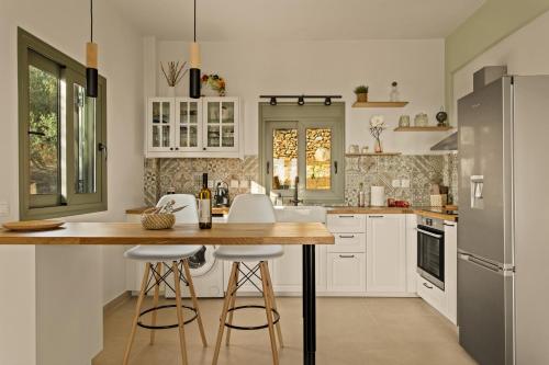 a kitchen with white cabinets and a island with bar stools at Casa Mainotti - Villa in Mani in Nomitsís