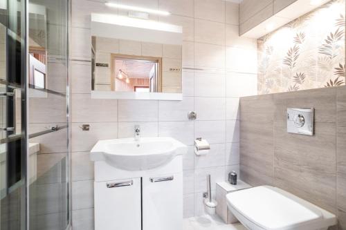 La salle de bains blanche est pourvue d'un lavabo et de toilettes. dans l'établissement Willa Ewa, à Jastarnia