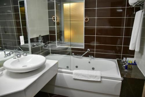 a bathroom with a sink and a tub and a mirror at Titanic Hotel & SPA in As Sulaymānīyah