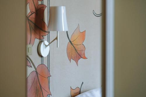 a lamp on a wall with autumn leaves on it at Conca Bella Boutique Hotel & Wine Experience in Vacallo