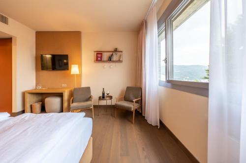 a hotel room with a bed and a desk and a window at Conca Bella Boutique Hotel & Wine Experience in Vacallo